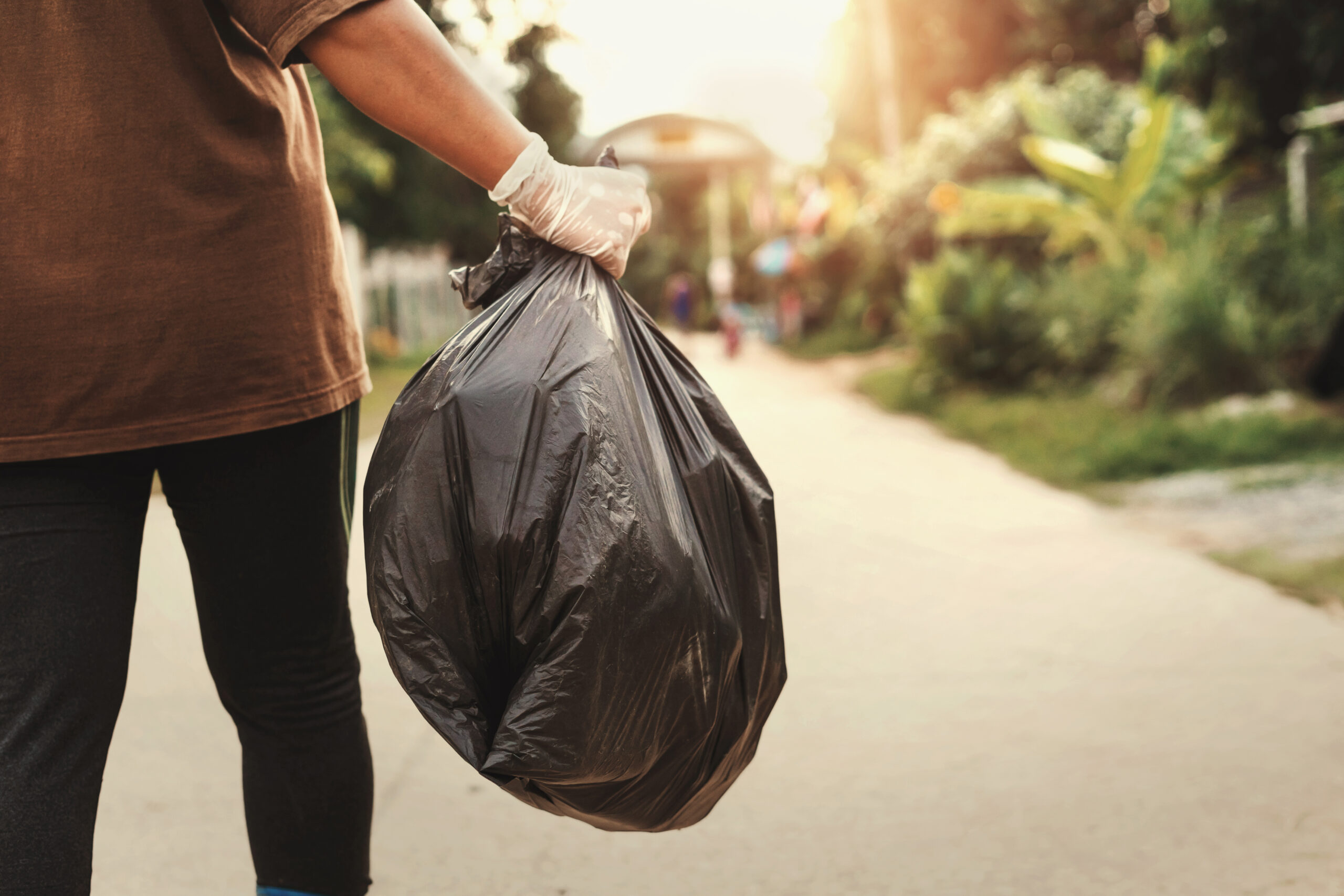 person hand holding garbage bag for recycle putting in to trash